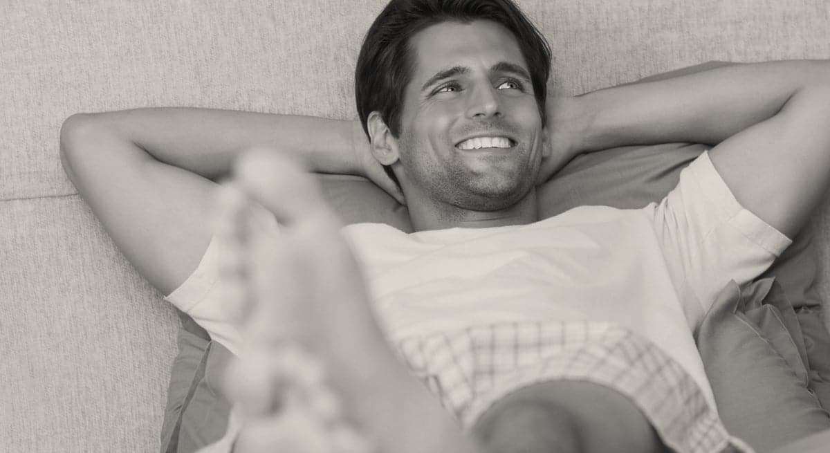 smilende mann med armene bak hodet