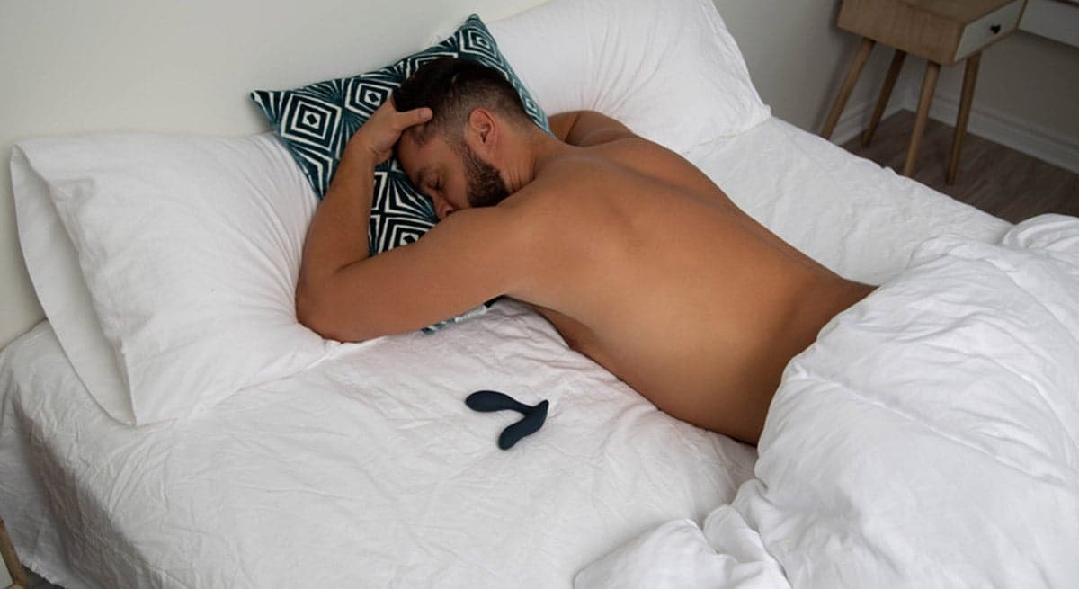 Mann ligger i sengen med prostatavibrator