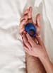 sexleketøy penisring we-vibe pivot vibrerende pensiring holdes i hånden på hvit seng 2
